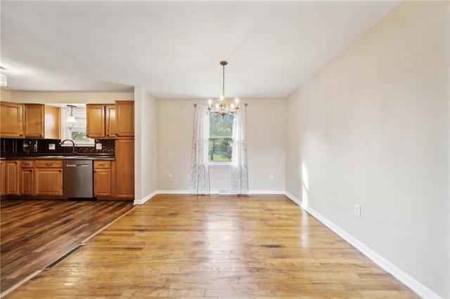 unfurnished dining area featuring a notable chandelier, sink, and light hardwood / wood-style flooring