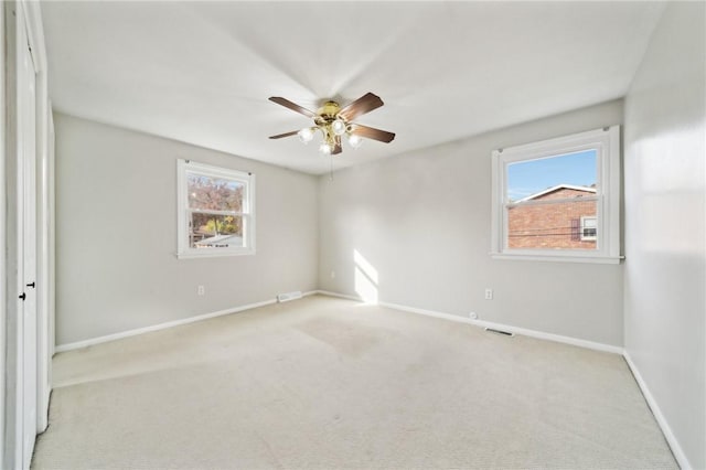 empty room featuring a healthy amount of sunlight, ceiling fan, and light colored carpet