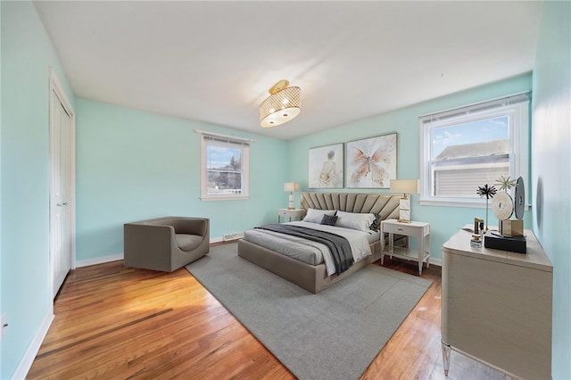 bedroom with multiple windows and light wood-type flooring