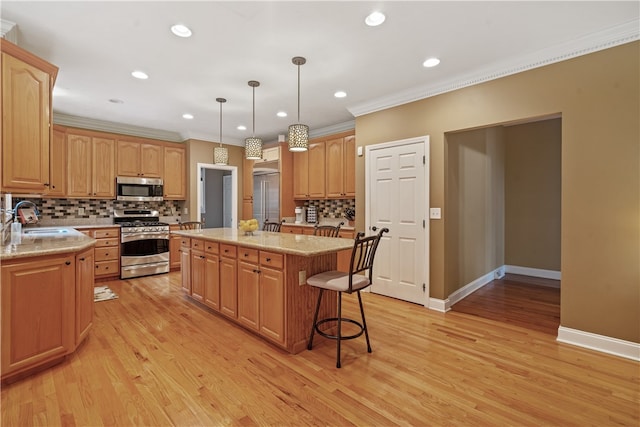 kitchen with light stone countertops, sink, light hardwood / wood-style flooring, a kitchen island, and appliances with stainless steel finishes