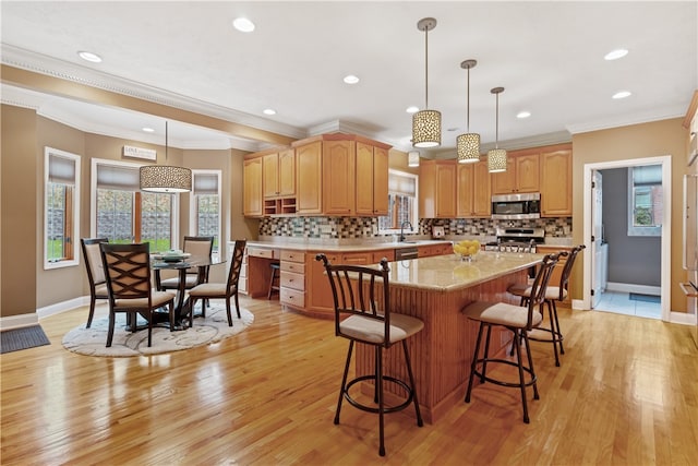 kitchen featuring appliances with stainless steel finishes, light hardwood / wood-style floors, and ornamental molding