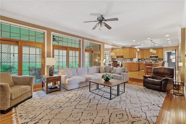 living room featuring ceiling fan, light wood-type flooring, and ornamental molding