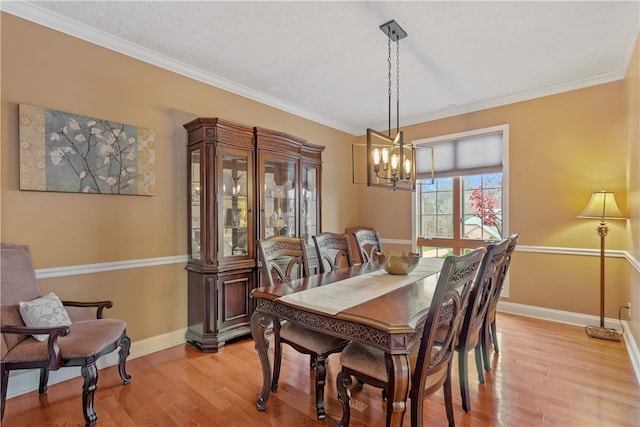 dining room featuring a notable chandelier, light wood-type flooring, and ornamental molding