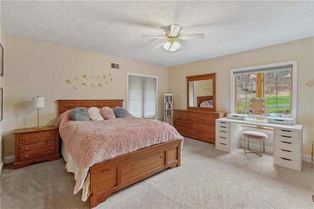 bedroom with light carpet, a textured ceiling, and ceiling fan