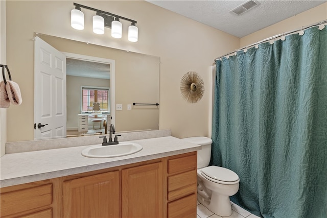 bathroom with tile patterned flooring, vanity, a textured ceiling, and toilet