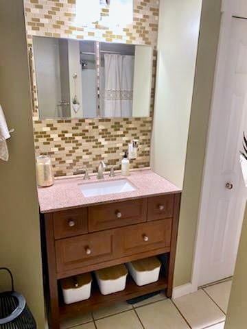 bathroom with tile patterned flooring, decorative backsplash, and vanity