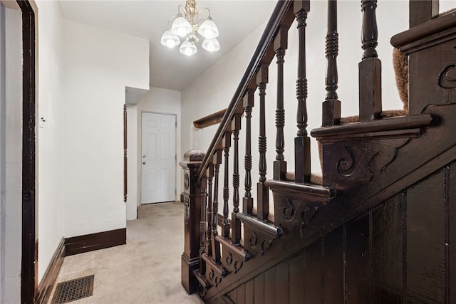 stairway featuring carpet flooring and an inviting chandelier