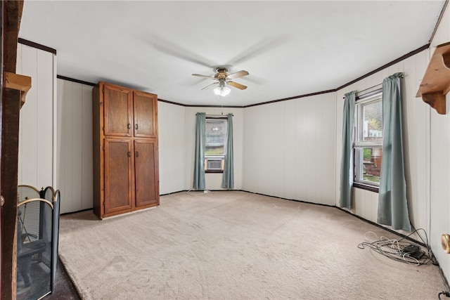 carpeted spare room with a wealth of natural light, ceiling fan, and ornamental molding