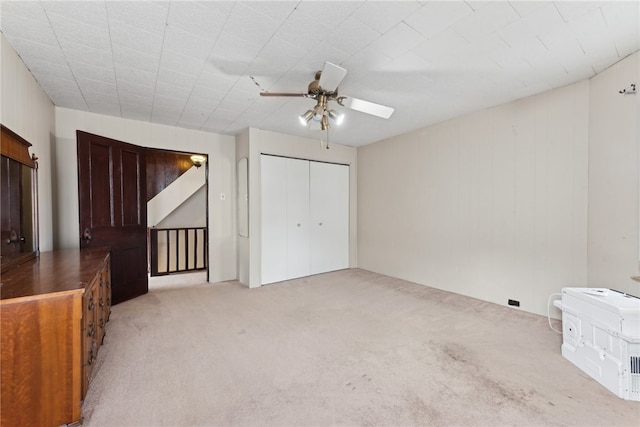 unfurnished bedroom featuring ceiling fan, a closet, and light colored carpet