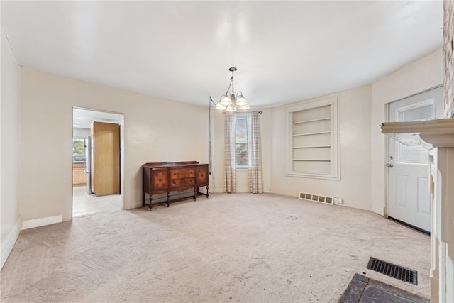 carpeted empty room featuring a chandelier and built in features