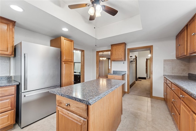 kitchen with decorative backsplash, stainless steel fridge, ceiling fan, light tile patterned floors, and a kitchen island