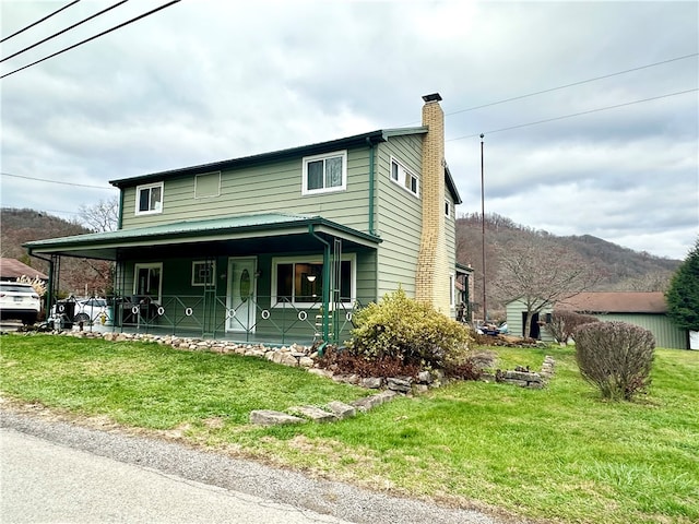 view of front of house featuring covered porch, a mountain view, and a front lawn