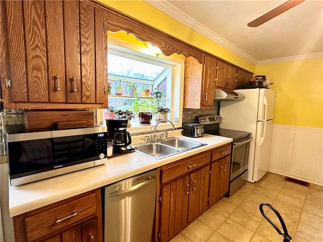 kitchen with sink, tasteful backsplash, appliances with stainless steel finishes, light tile patterned flooring, and ornamental molding