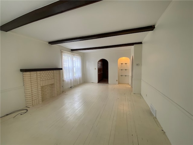 unfurnished living room featuring beam ceiling, a fireplace, and light hardwood / wood-style flooring