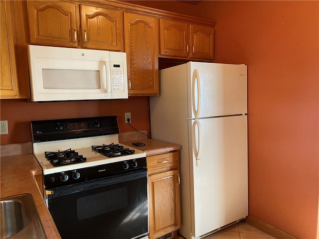 kitchen featuring sink, light tile patterned flooring, and white appliances