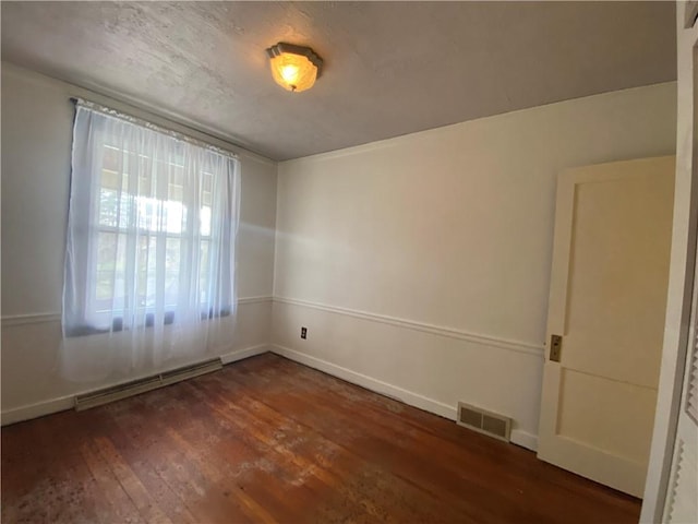 spare room with a baseboard radiator and dark hardwood / wood-style floors