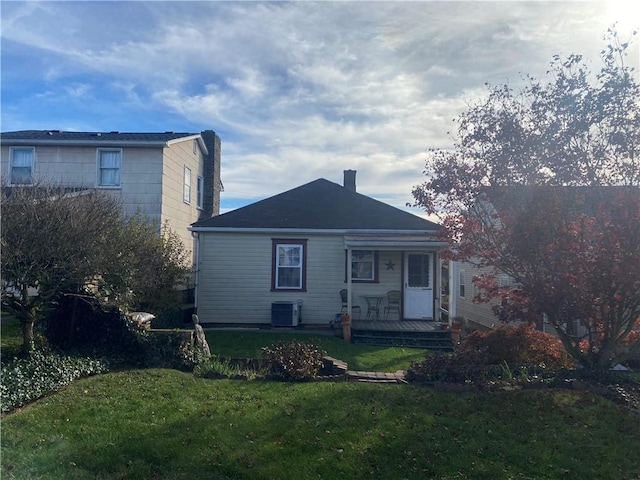 rear view of house featuring a lawn and central AC unit