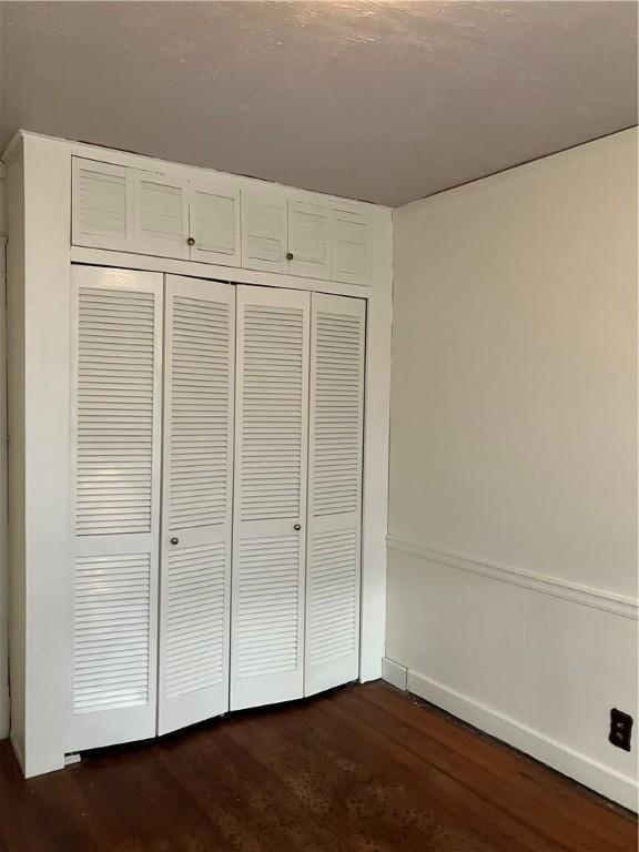 unfurnished bedroom featuring dark hardwood / wood-style flooring and a closet