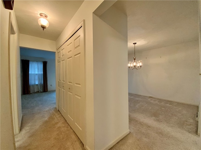 hall featuring light carpet and a chandelier