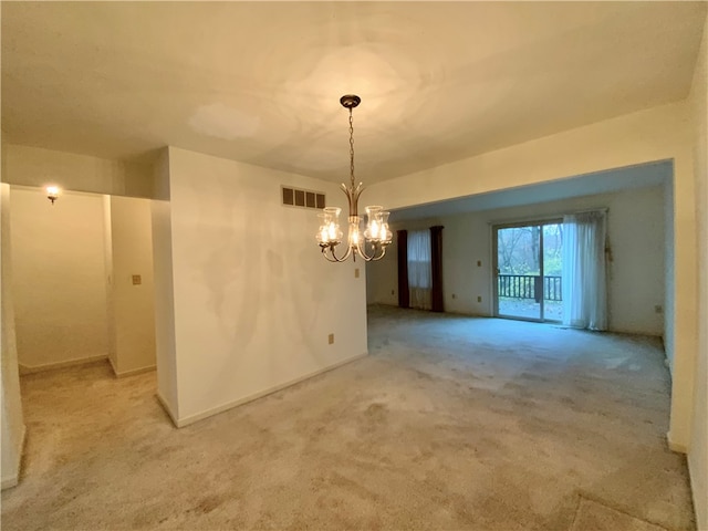 spare room featuring a chandelier and light colored carpet