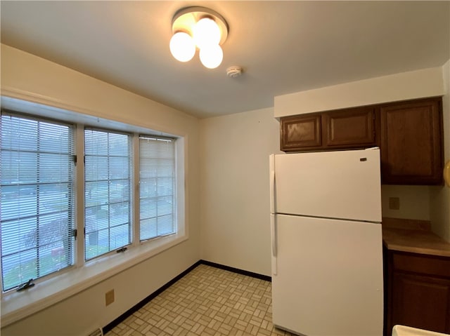 kitchen featuring dark brown cabinets, white fridge, and a healthy amount of sunlight