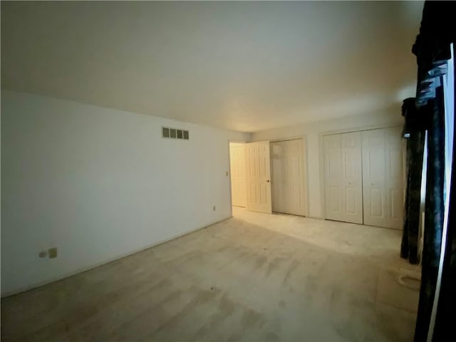 unfurnished bedroom with light carpet and two closets