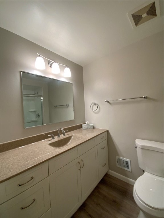 bathroom featuring hardwood / wood-style floors, vanity, a shower with door, and toilet