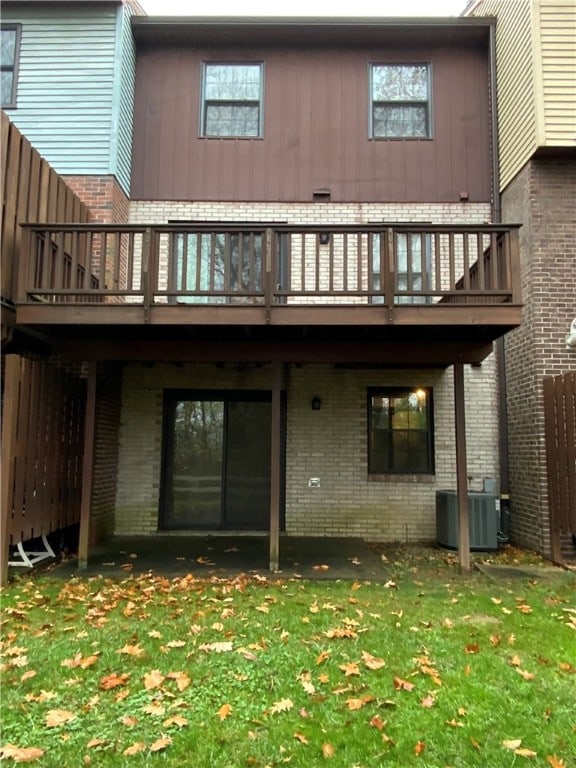 rear view of property featuring a lawn and central air condition unit