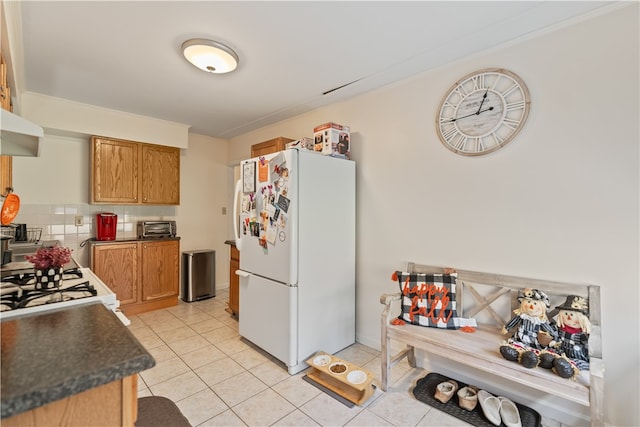 kitchen with decorative backsplash, white fridge, light tile patterned flooring, and exhaust hood