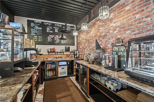 bar with pendant lighting, dark stone countertops, and brick wall