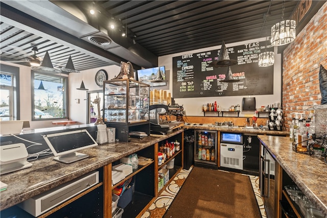 bar featuring stone counters, hanging light fixtures, and brick wall