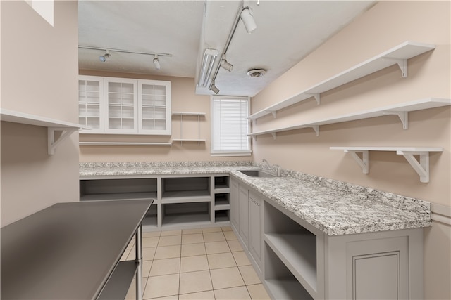 kitchen with gray cabinetry, sink, light tile patterned floors, and rail lighting