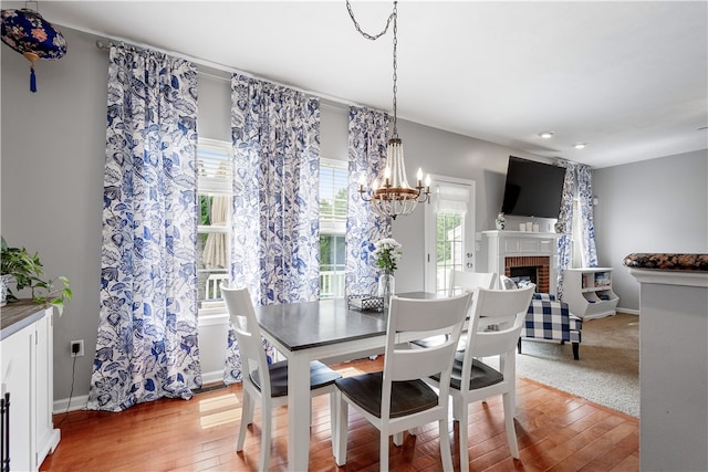 dining area with hardwood / wood-style floors, a chandelier, and a brick fireplace