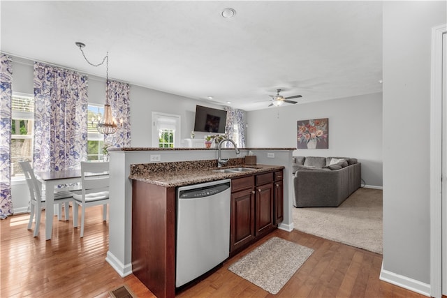 kitchen with sink, stainless steel dishwasher, pendant lighting, ceiling fan with notable chandelier, and light wood-type flooring