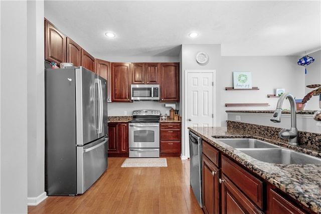 kitchen featuring light hardwood / wood-style floors, sink, stainless steel appliances, and dark stone counters