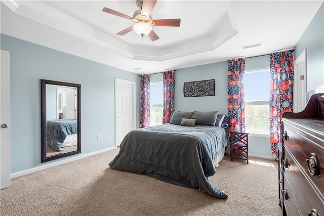 bedroom featuring ceiling fan, light colored carpet, crown molding, and a tray ceiling