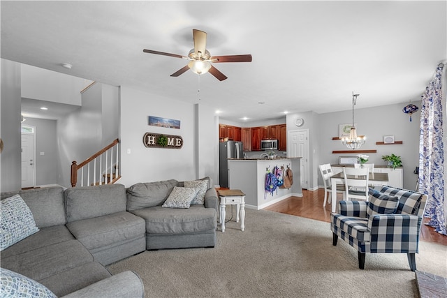 living room with ceiling fan with notable chandelier and light hardwood / wood-style flooring