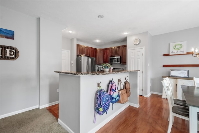 kitchen with a chandelier, dark stone counters, dark hardwood / wood-style floors, and appliances with stainless steel finishes