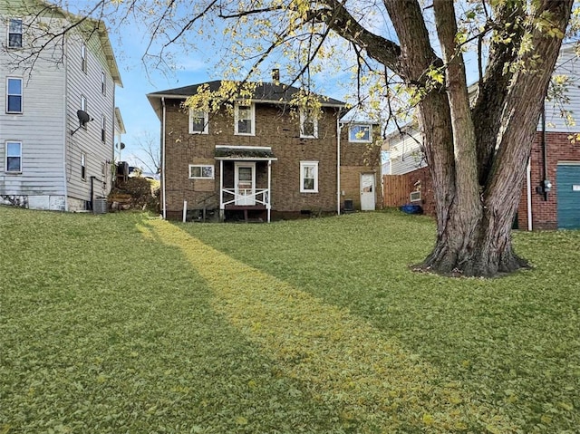 rear view of house featuring a lawn and central AC