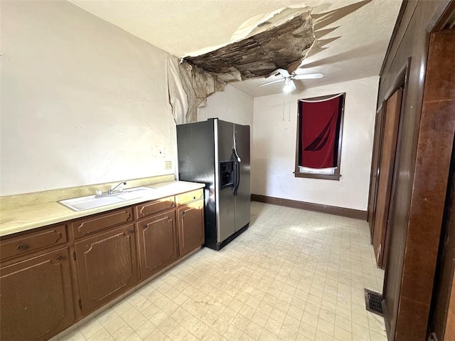 kitchen featuring dark brown cabinetry, ceiling fan, sink, stainless steel fridge with ice dispenser, and a textured ceiling