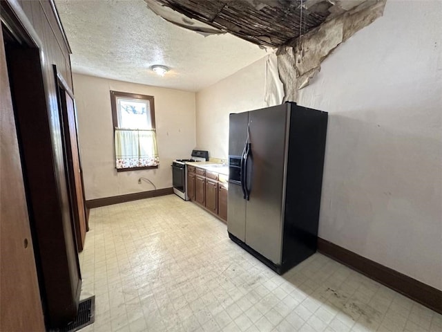 kitchen featuring white range with gas stovetop, dark brown cabinets, a textured ceiling, and black fridge