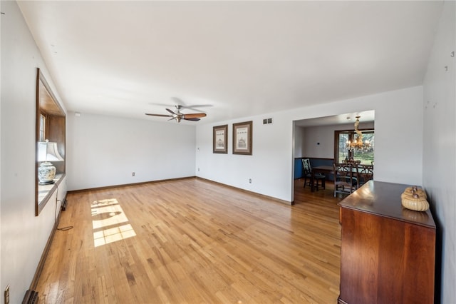 living room with ceiling fan with notable chandelier and light hardwood / wood-style flooring