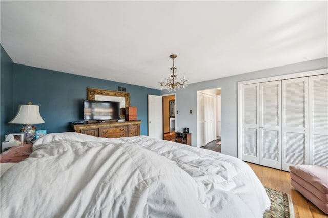 bedroom with light hardwood / wood-style floors, an inviting chandelier, and a closet