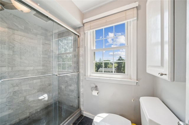 bathroom featuring a shower with shower door and toilet