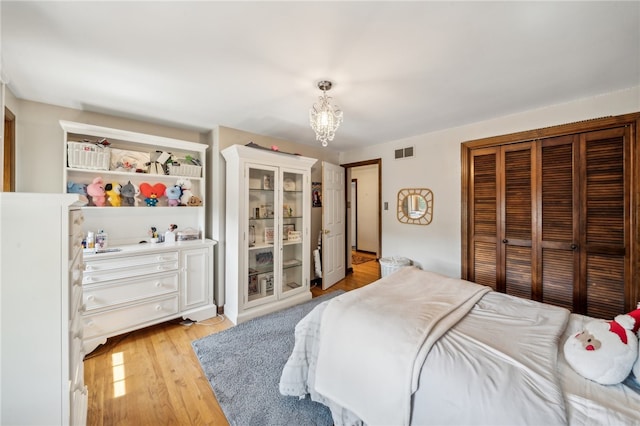 bedroom featuring a closet, a notable chandelier, and light wood-type flooring