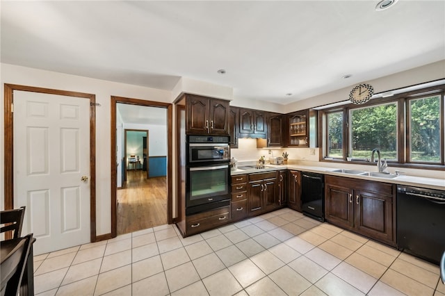 kitchen with black appliances, dark brown cabinetry, sink, and light tile patterned floors