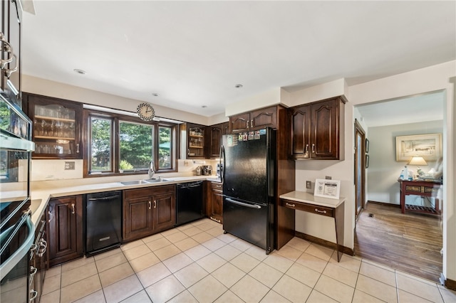 kitchen with dark brown cabinets, sink, light hardwood / wood-style floors, and black appliances