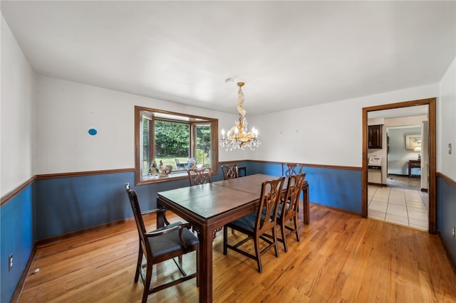 dining area with light hardwood / wood-style floors and an inviting chandelier