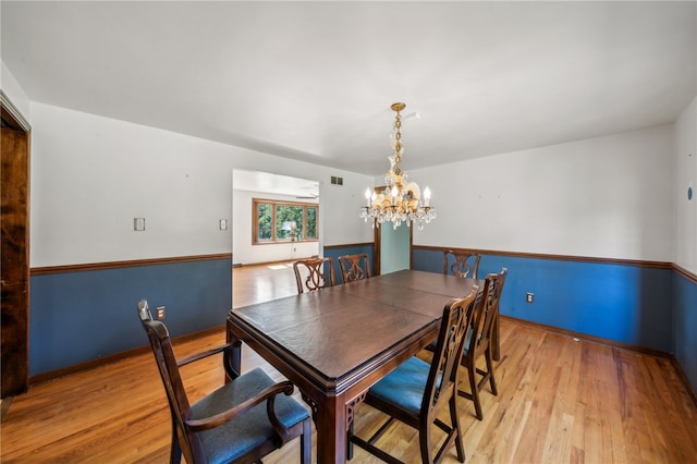 dining room with light hardwood / wood-style flooring and a chandelier