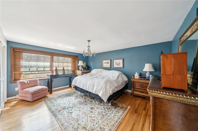 bedroom with a notable chandelier and light wood-type flooring